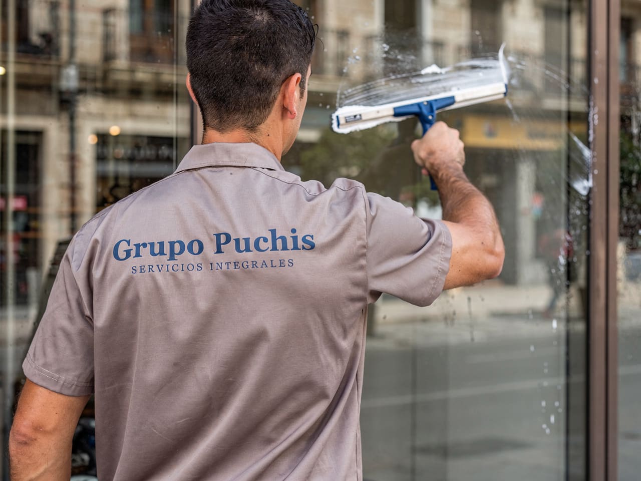 Operario de Grupo Puchis limpiando un escaparate con mojador