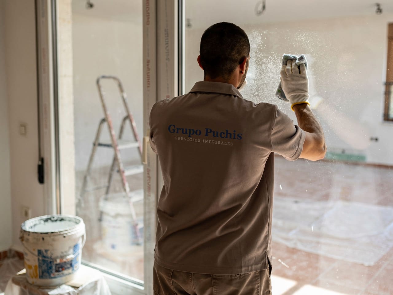 Operario de Grupo Puchis retirando el polvo de obra de una ventana en una vivienda recién reformada